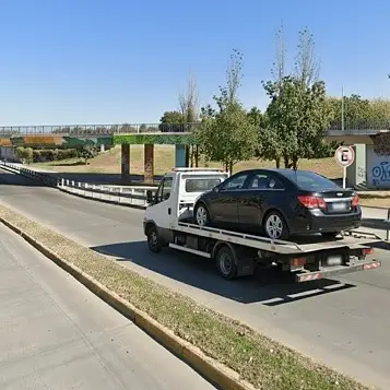 Grúa remolcando auto negro por avenida de Mendoza